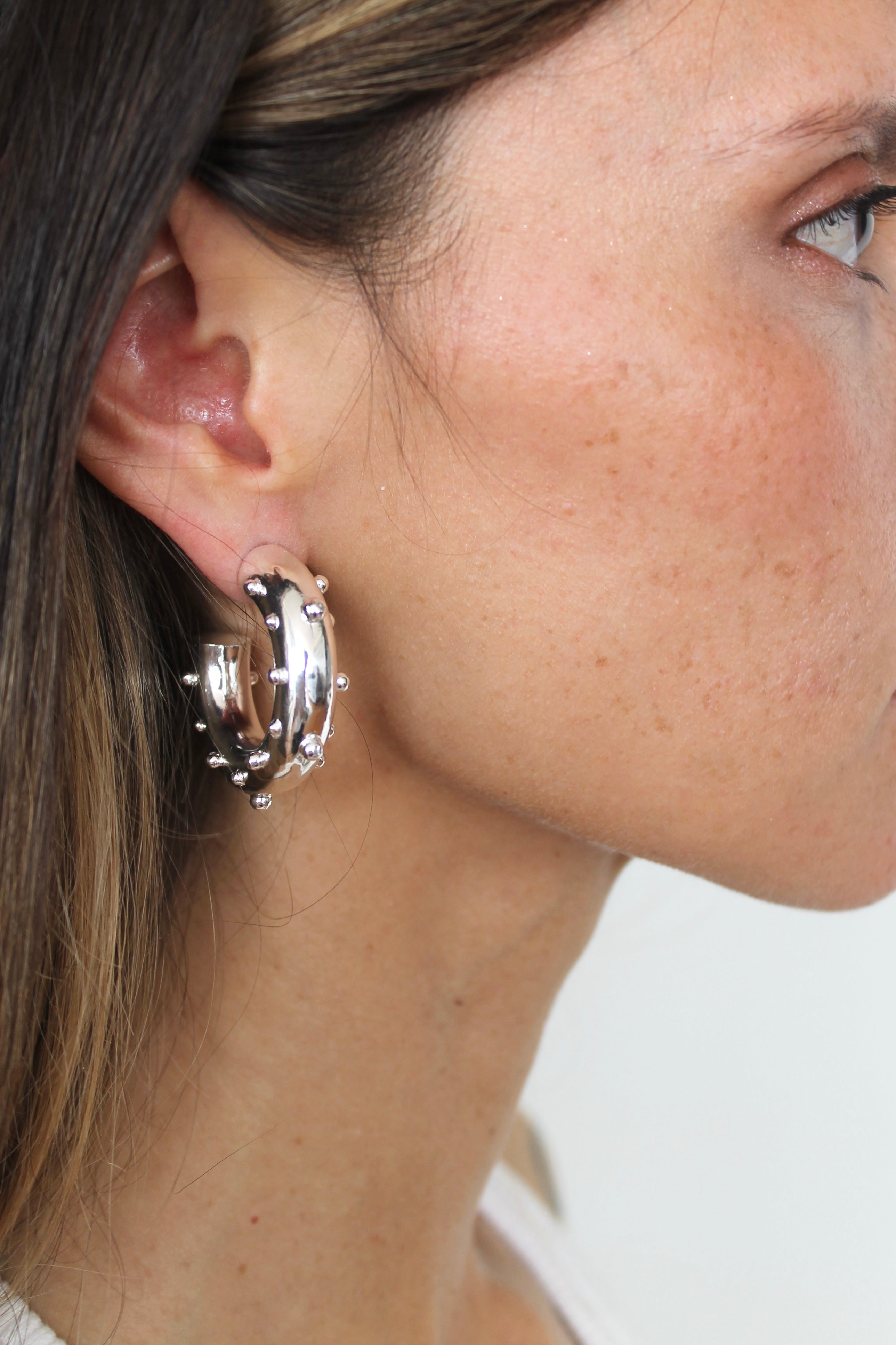 Close-up of a woman wearing a hoop earring with a blurred background
