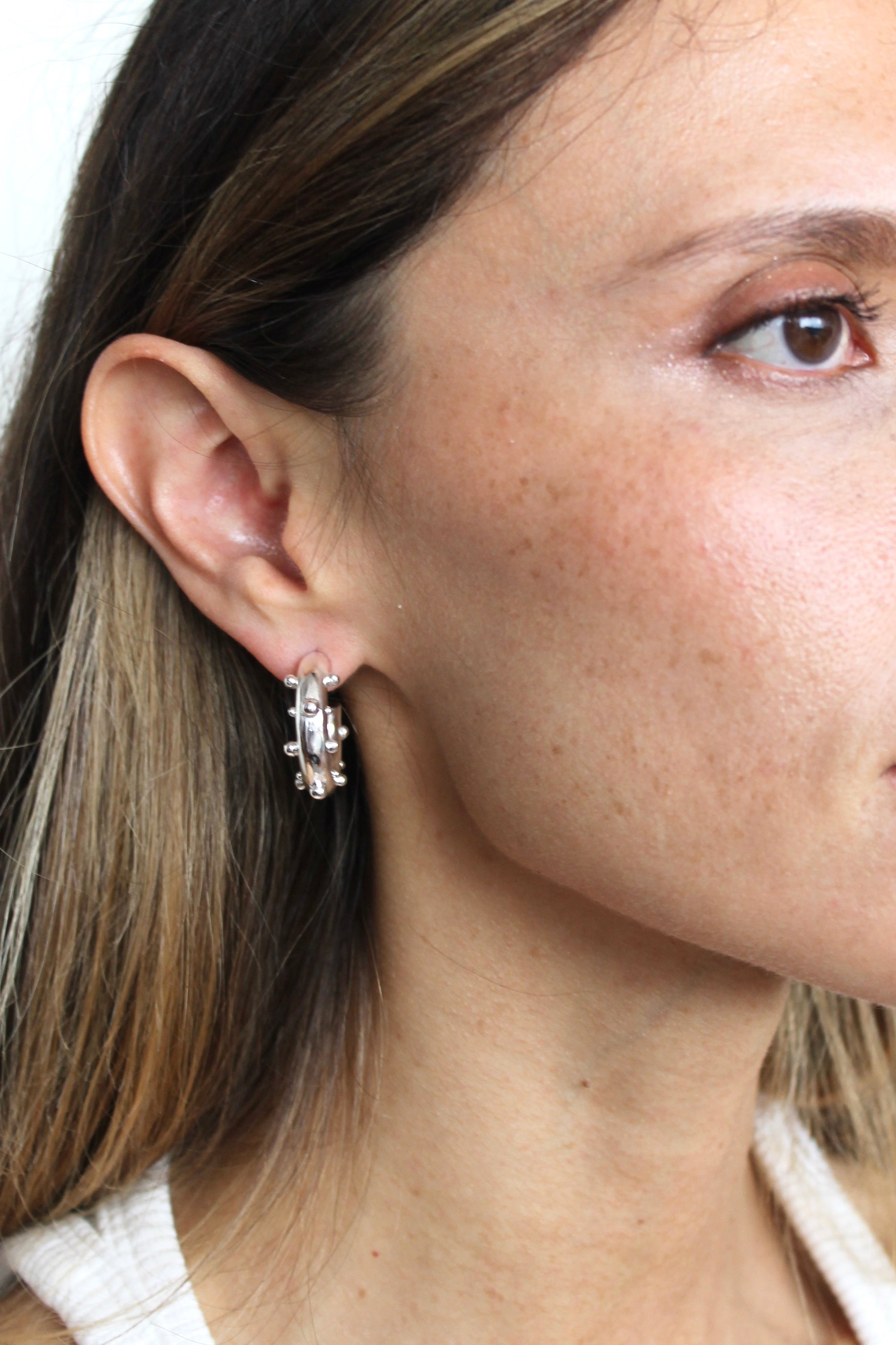 Close-up of a woman wearing a silver earring with a gemstone.