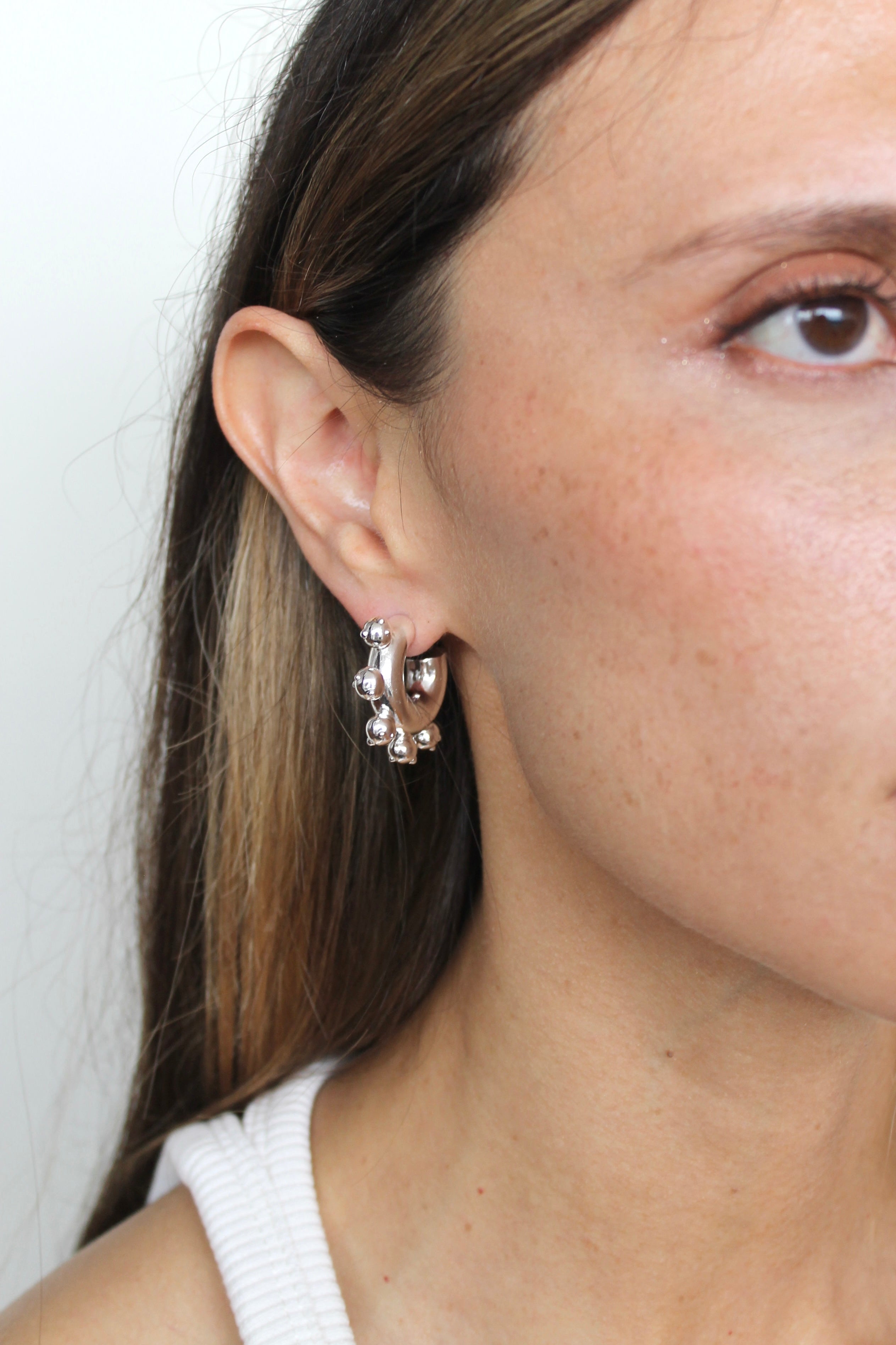 Close-up of a person wearing a silver earring with a white background